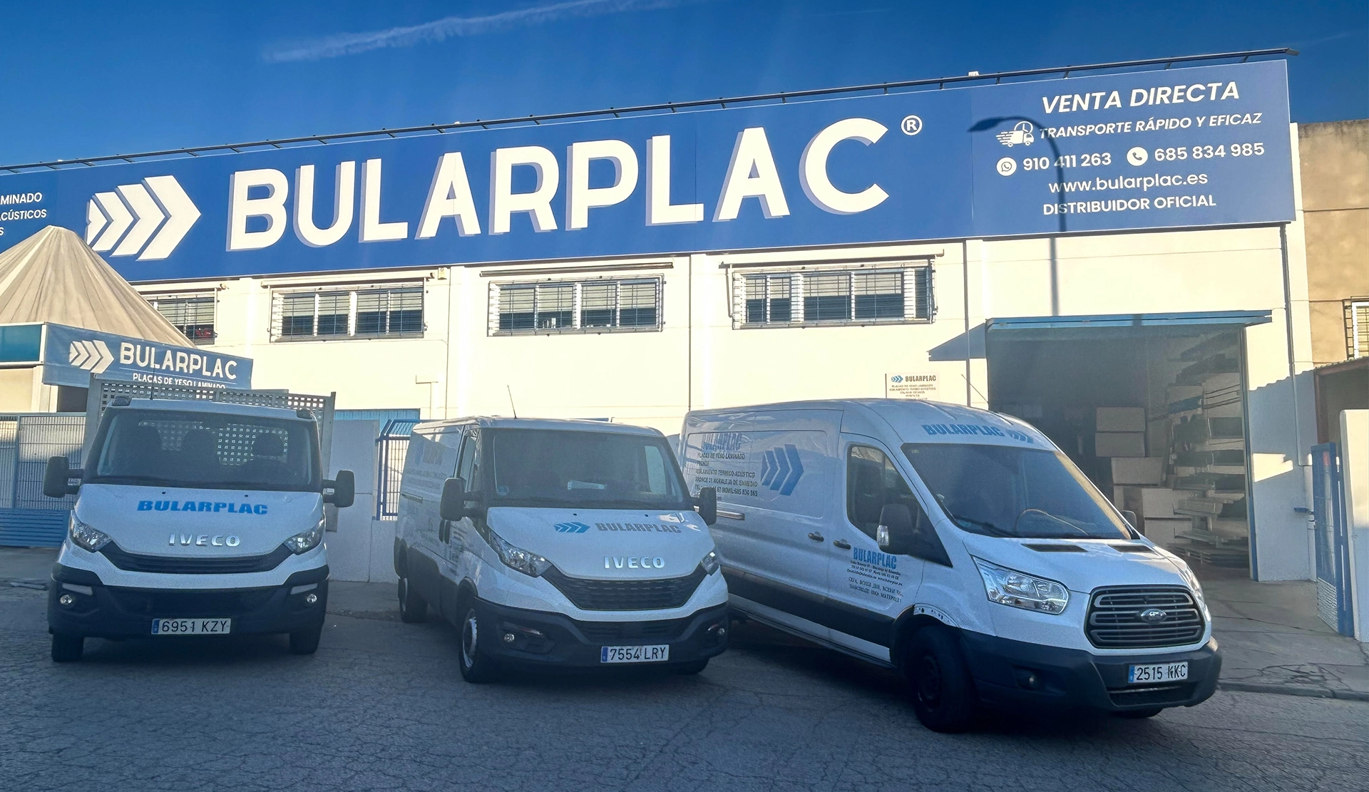 Placas de yeso laminado en Madrid con fachada y furgonetas de reparto de Bularplac